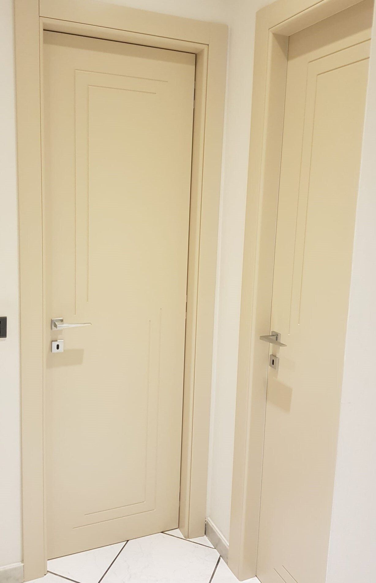 Due porte interne di colore chiaro, una accanto all'altra, contro una parete bianca.