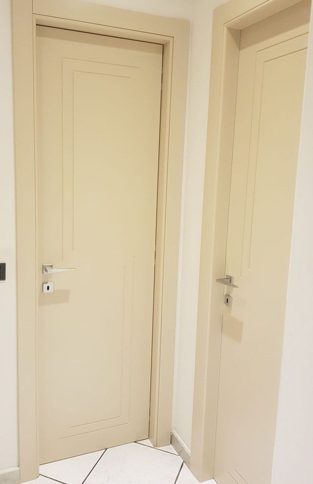 Due porte interne di colore chiaro, una accanto all'altra, contro una parete bianca.