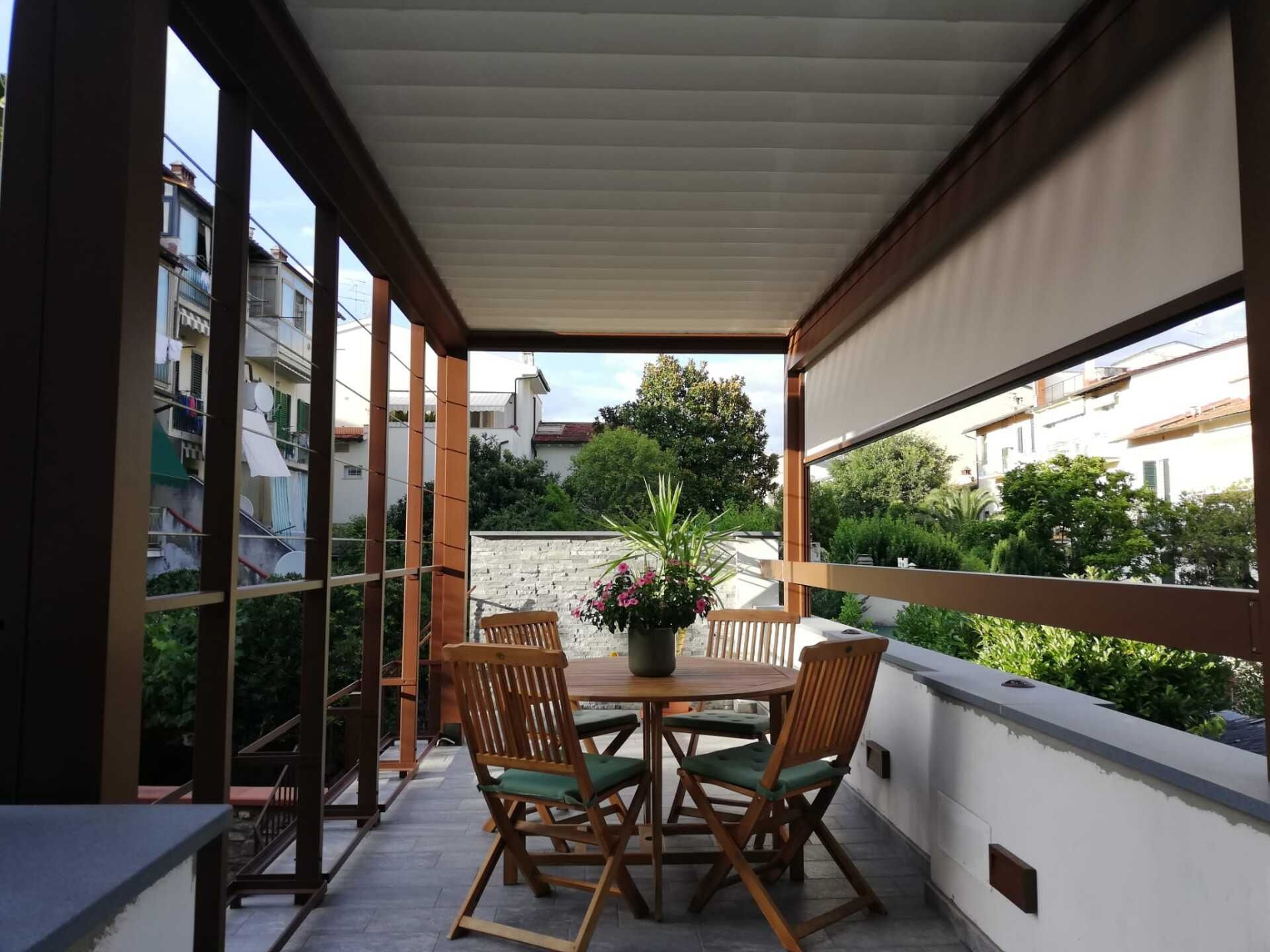 Patio esterno con mobili in legno, con vista su alberi ed edifici.