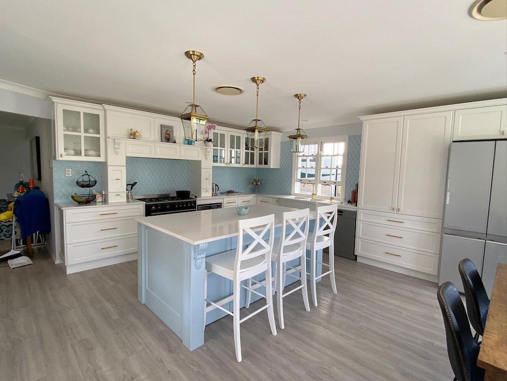 A Kitchen With A Blue Island And White Chairs — Infinity Kitchens & Cabinets in Ballina, NSW