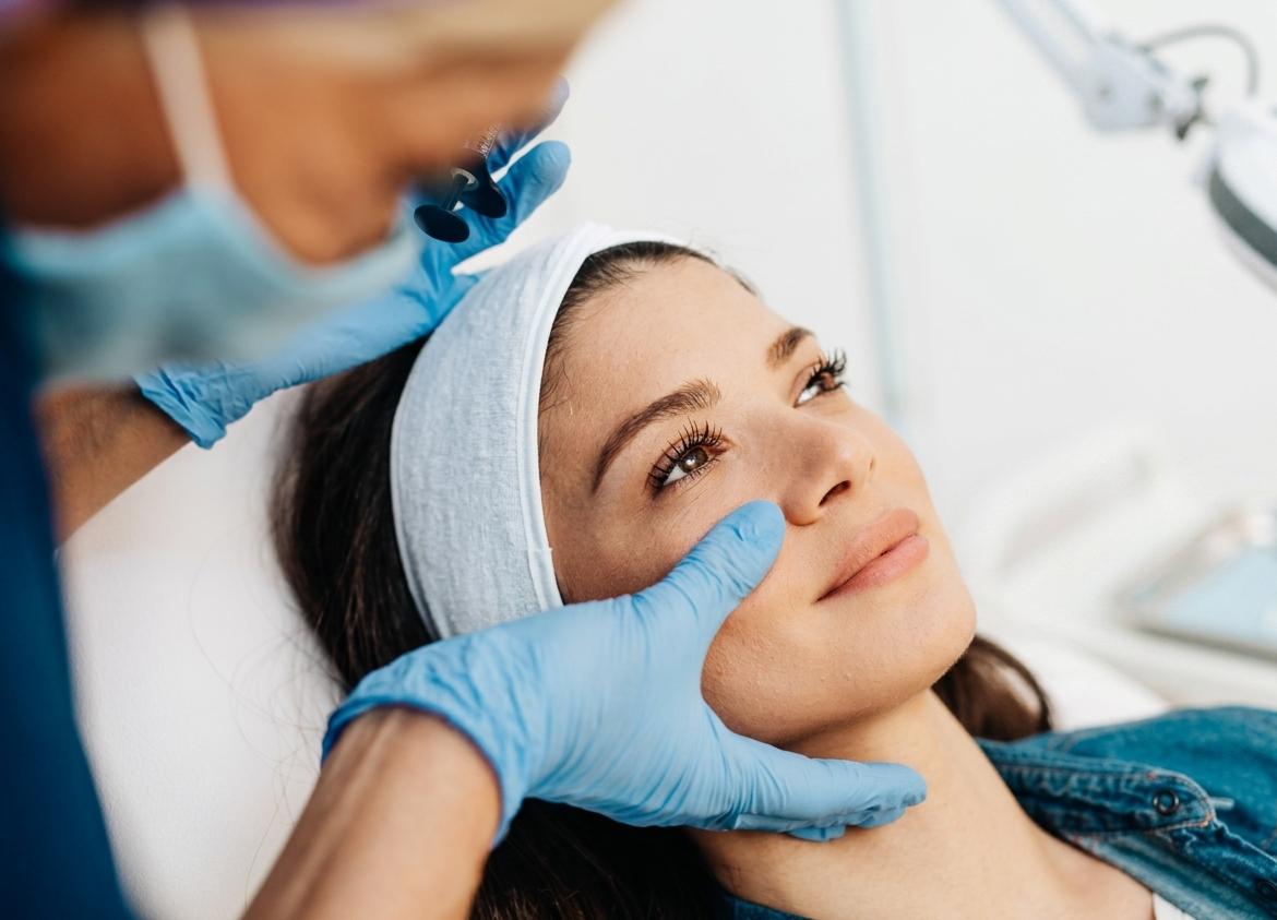 Un'estetista con i guanti blu esamina delicatamente il viso di una donna in un ambiente termale.