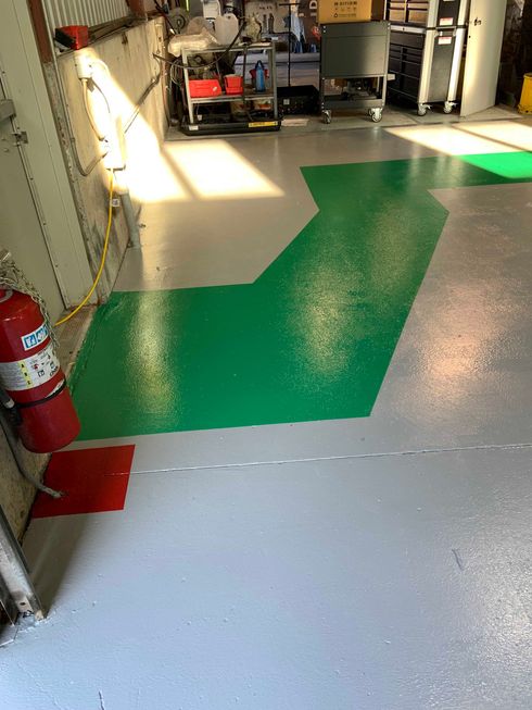 Un sol vert et blanc brillant dans un garage, avec un extincteur sur la gauche.