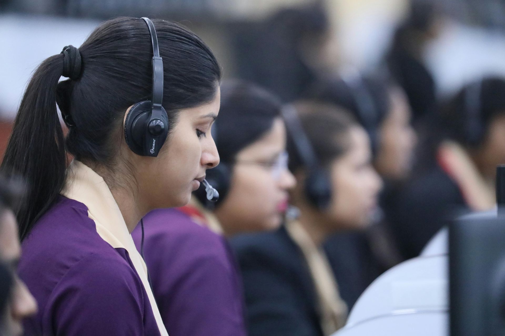 A woman wearing headphones is sitting in front of a computer.