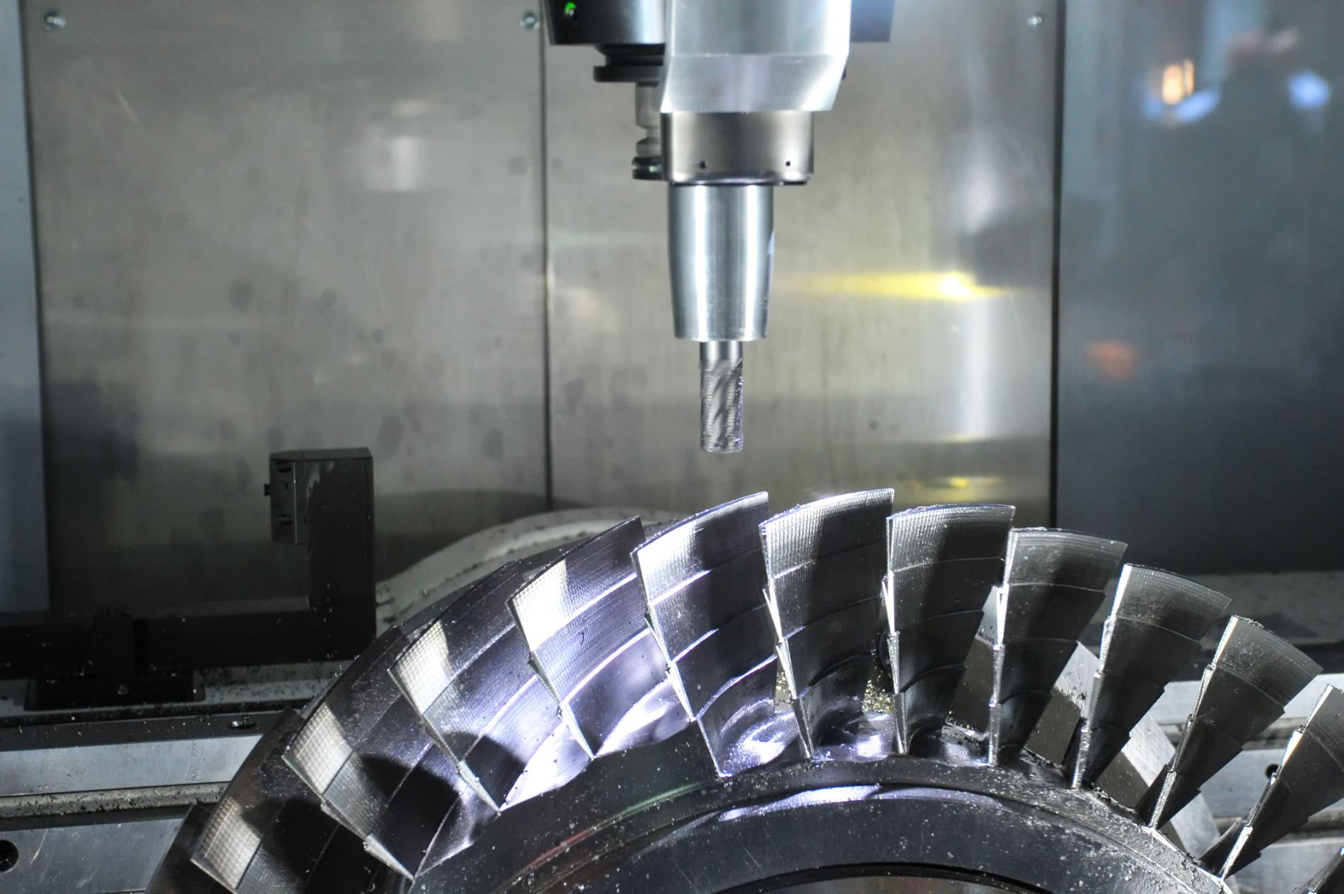 Macchina CNC che taglia un componente di turbina o ingranaggio in metallo lucido con un utensile di fresatura