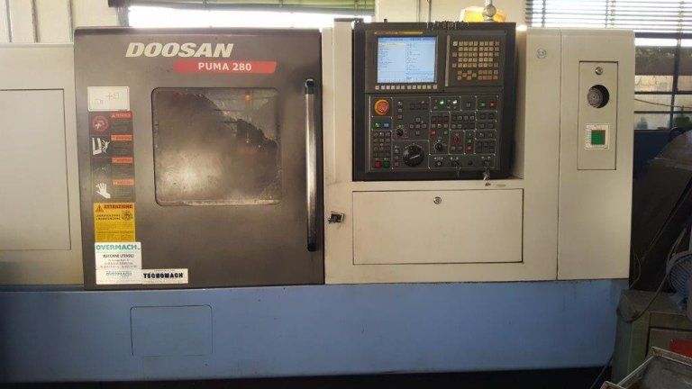 Fresatrice CNC Doosan con pannello di controllo e area di lavoro chiusa in un'officina industriale.