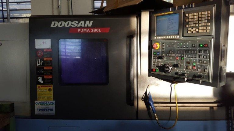 Macchina CNC Doosan con armadio scuro e pannello di controllo illuminato in un'officina industriale.