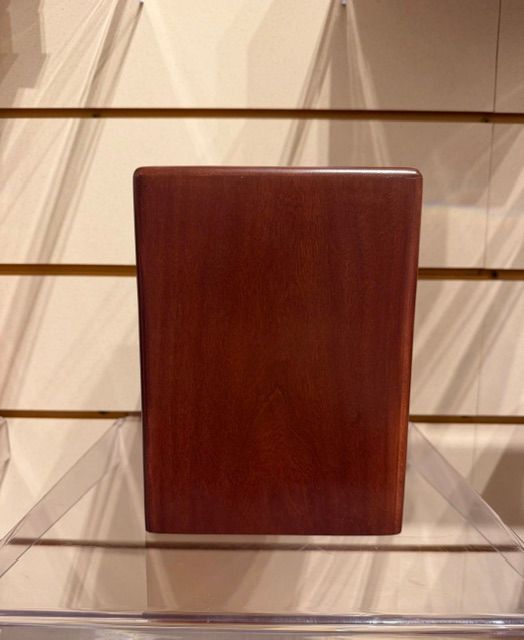Dark wooden plaque on a clear stand against a slatwall display background