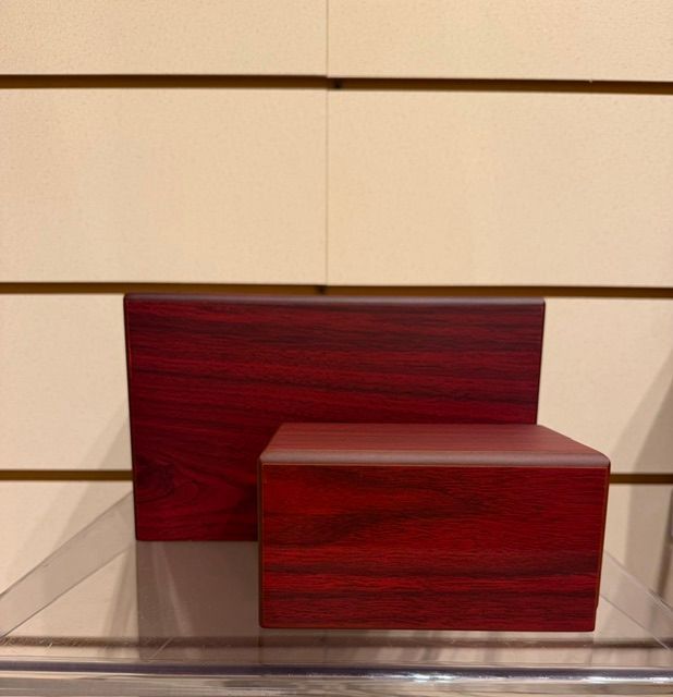 Two red wooden display blocks on a shelf against a beige paneled wall.