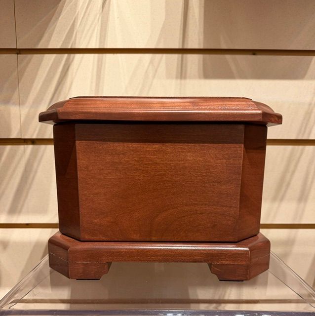 Small polished wooden box with a hinged lid on a clear display shelf.