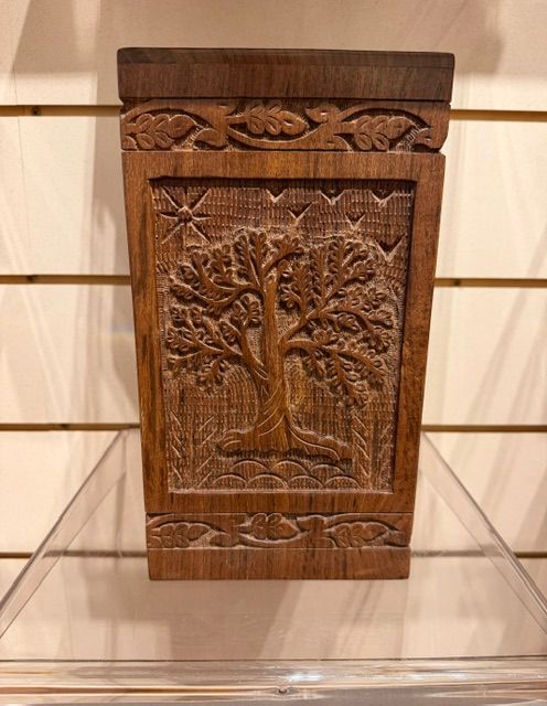 Carved wooden decorative panel with a tree motif displayed on a clear stand.