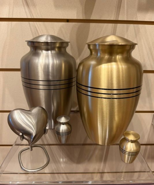 Display of metallic urns and keepsakes in silver and gold on a shelf
