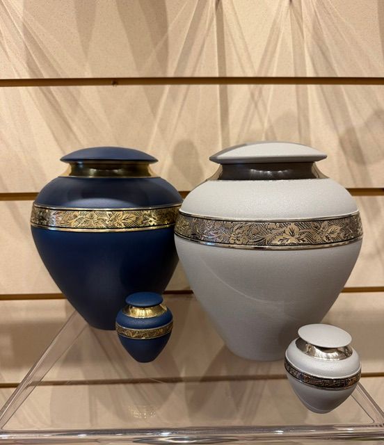 Blue and white decorative urns with gold bands displayed on glass shelves.