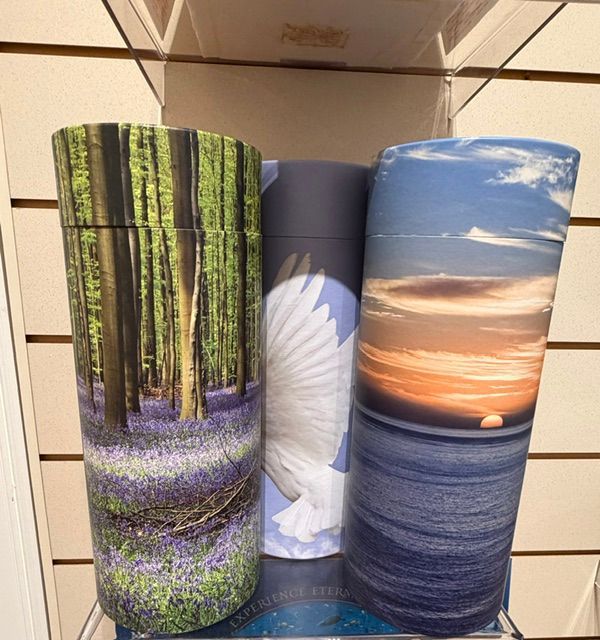 Three decorative rolls with forest, flower, and sunset ocean scenes on a store shelf.