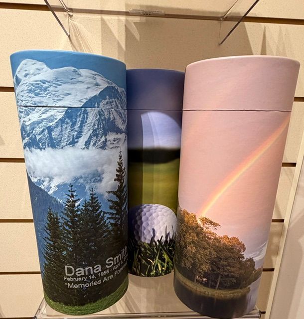 Three colorful travel tumblers with scenic mountain and rainbow prints on a shelf