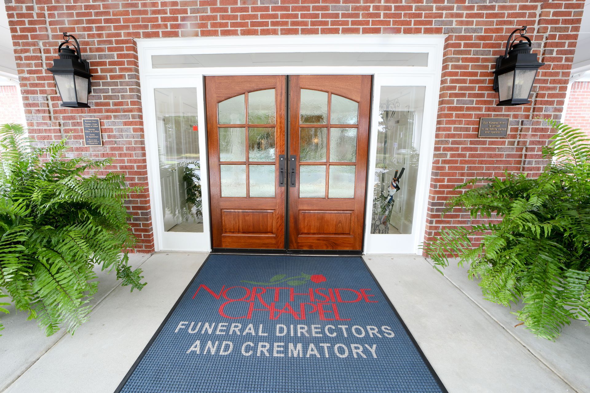 Entrance to an Alexandria Funeral Directors and Crematory building with wooden double doors and brick facade
