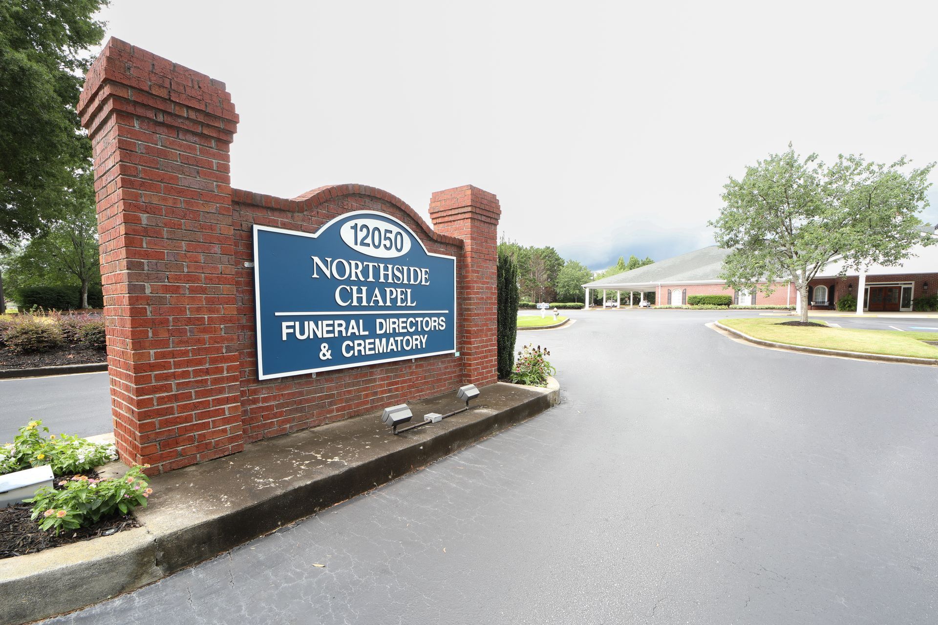 Brick entrance sign for North Hills Nursery, with driveway and landscaped grounds on a cloudy day