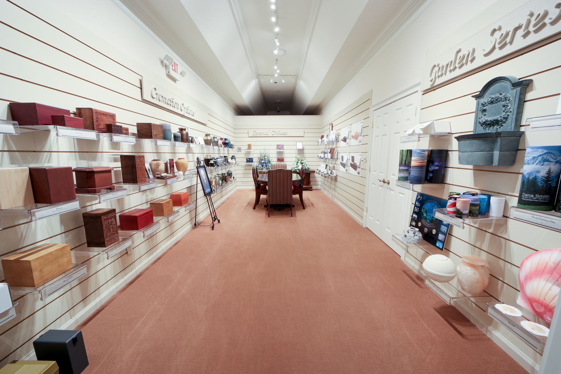 A long boutique aisle with shelves of colorful home decor and rugs under bright ceiling lights.