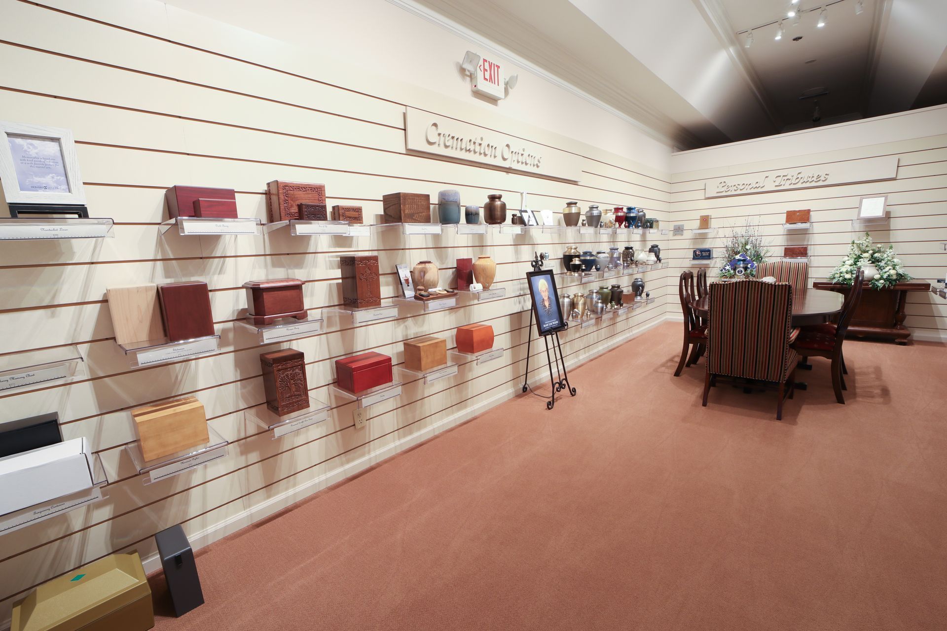 Showroom interior with wall-mounted brochures, a display rack, and a wooden table on a pink carpet.