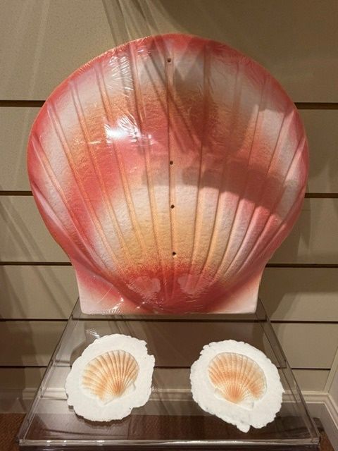 Large pink seashell display with two smaller shell pieces on a shelf.
