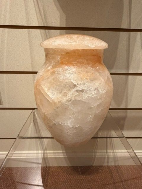 White ceramic jar with a narrow neck and flared rim on a display stand