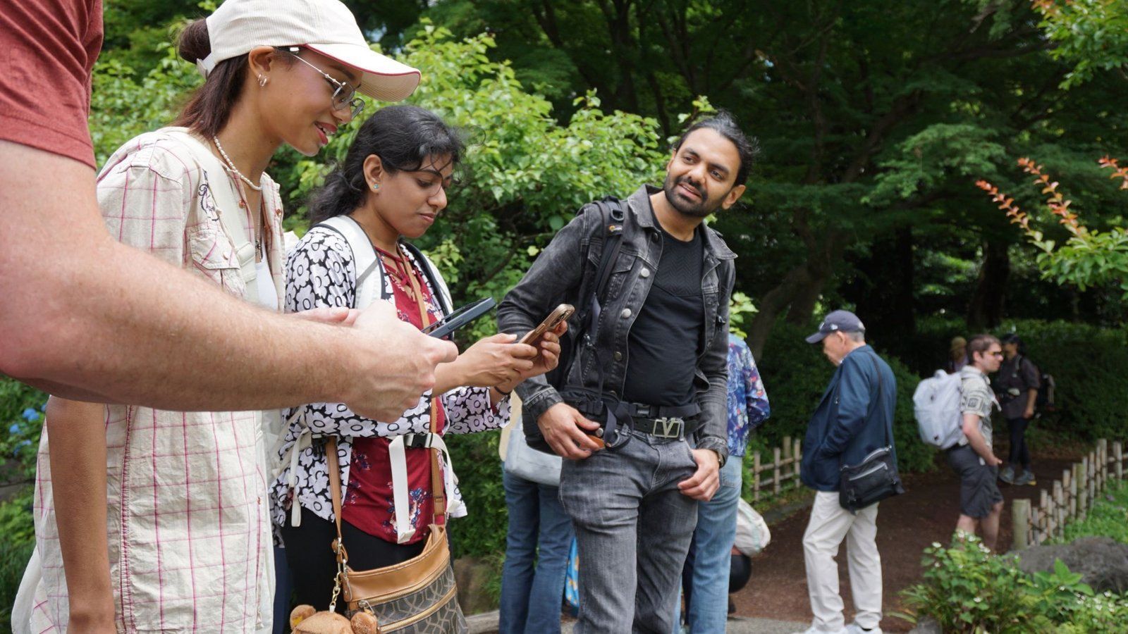 Guests following a Sunrise Adventure guide's directions on their phones in a Tokyo garden