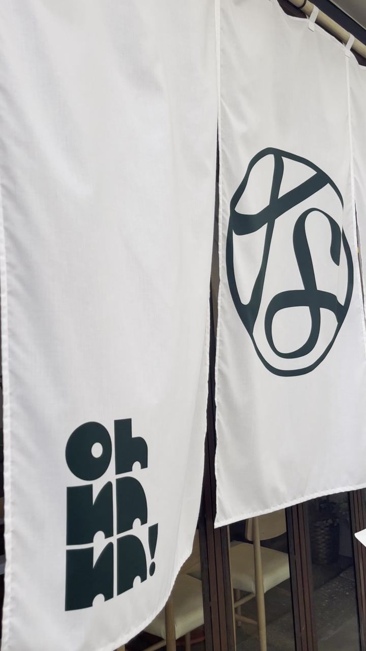 The entrance to Oh Nana, with white noren curtains and the Oh Nana logo