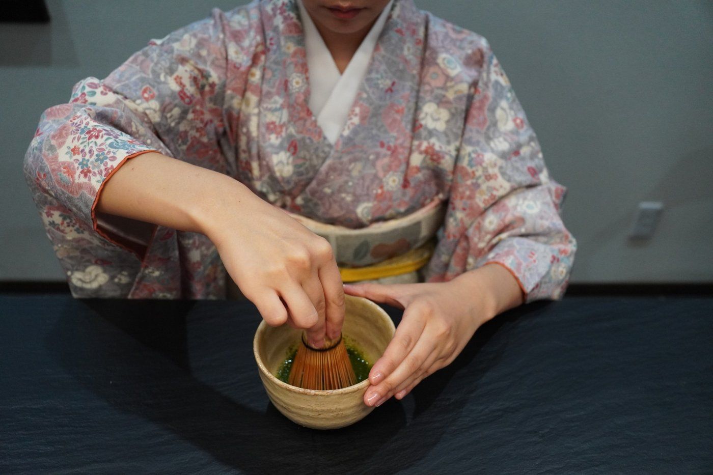 A tea master in a kimono whisking matcha