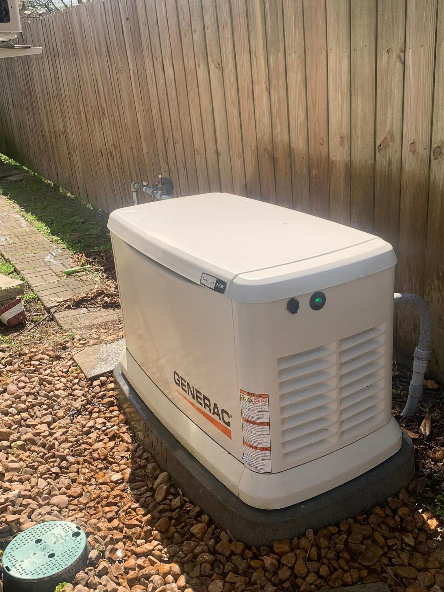White outdoor generator beside a wooden fence on gravel in a backyard area
