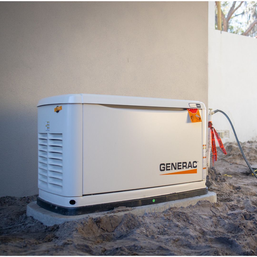 White Generac backup generator installed beside a house wall on a dirt patch
