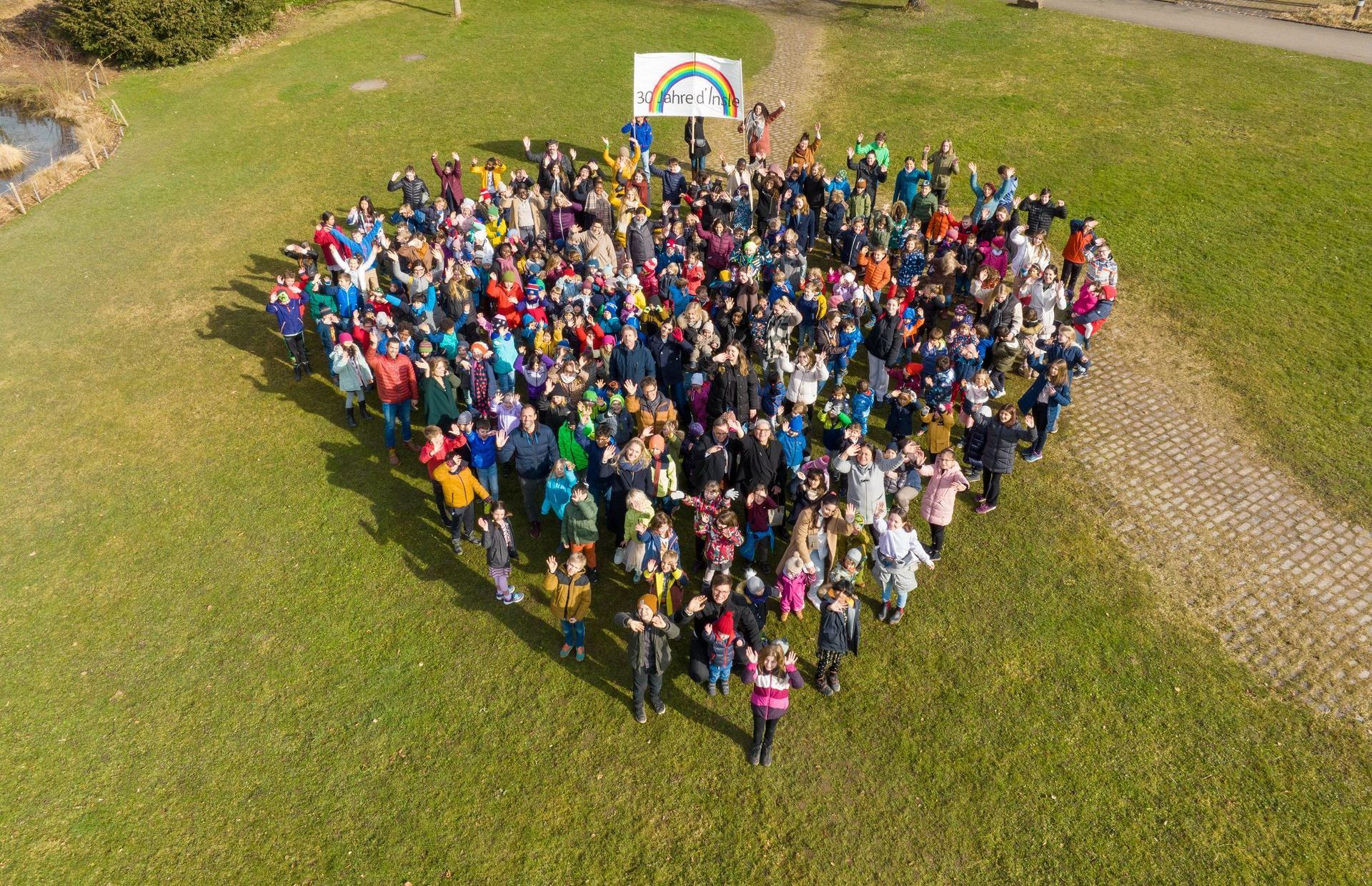 An aerial view of a large group of people standing in the shape of a heart.