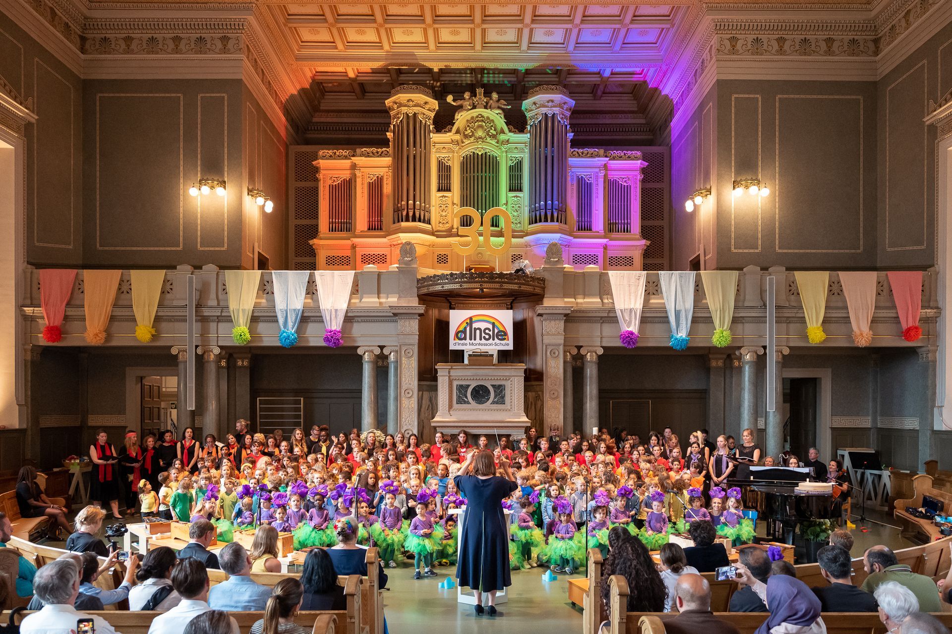 A woman is standing in front of a large crowd of people in a church.