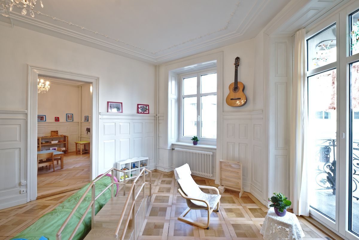 A living room with a rocking chair and a guitar on the wall.