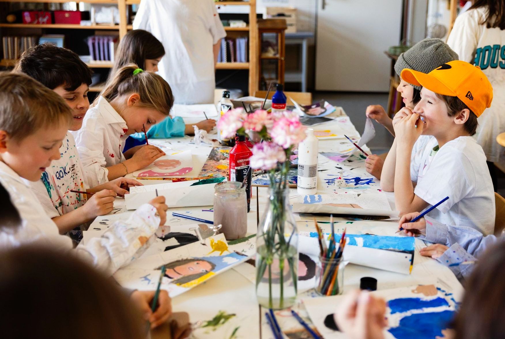 A group of children are sitting at a table painting.