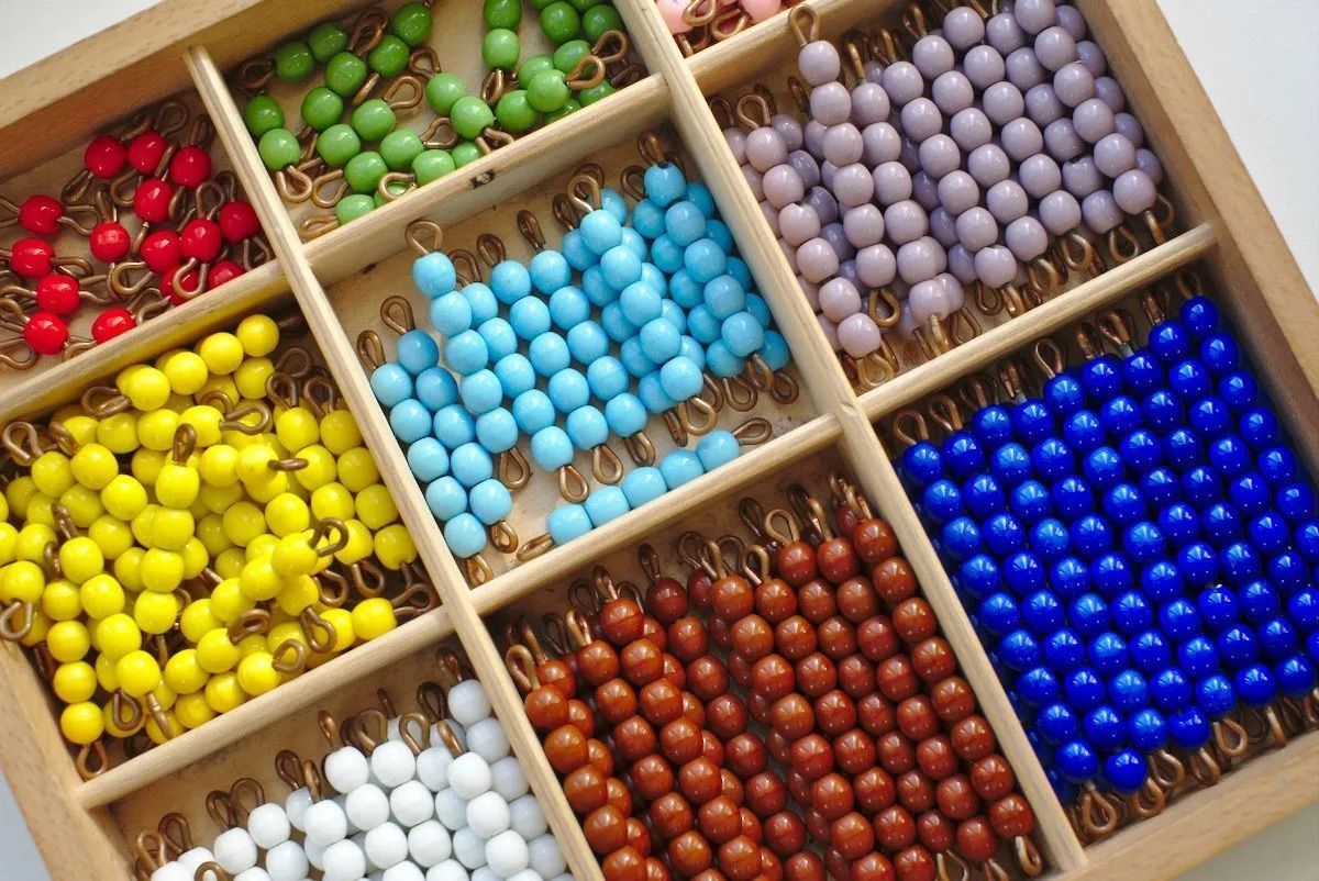 A wooden box filled with many different colored beads
