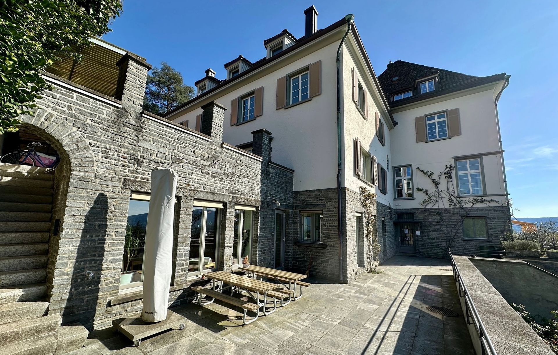 A large white and stone building with a patio in front of it.