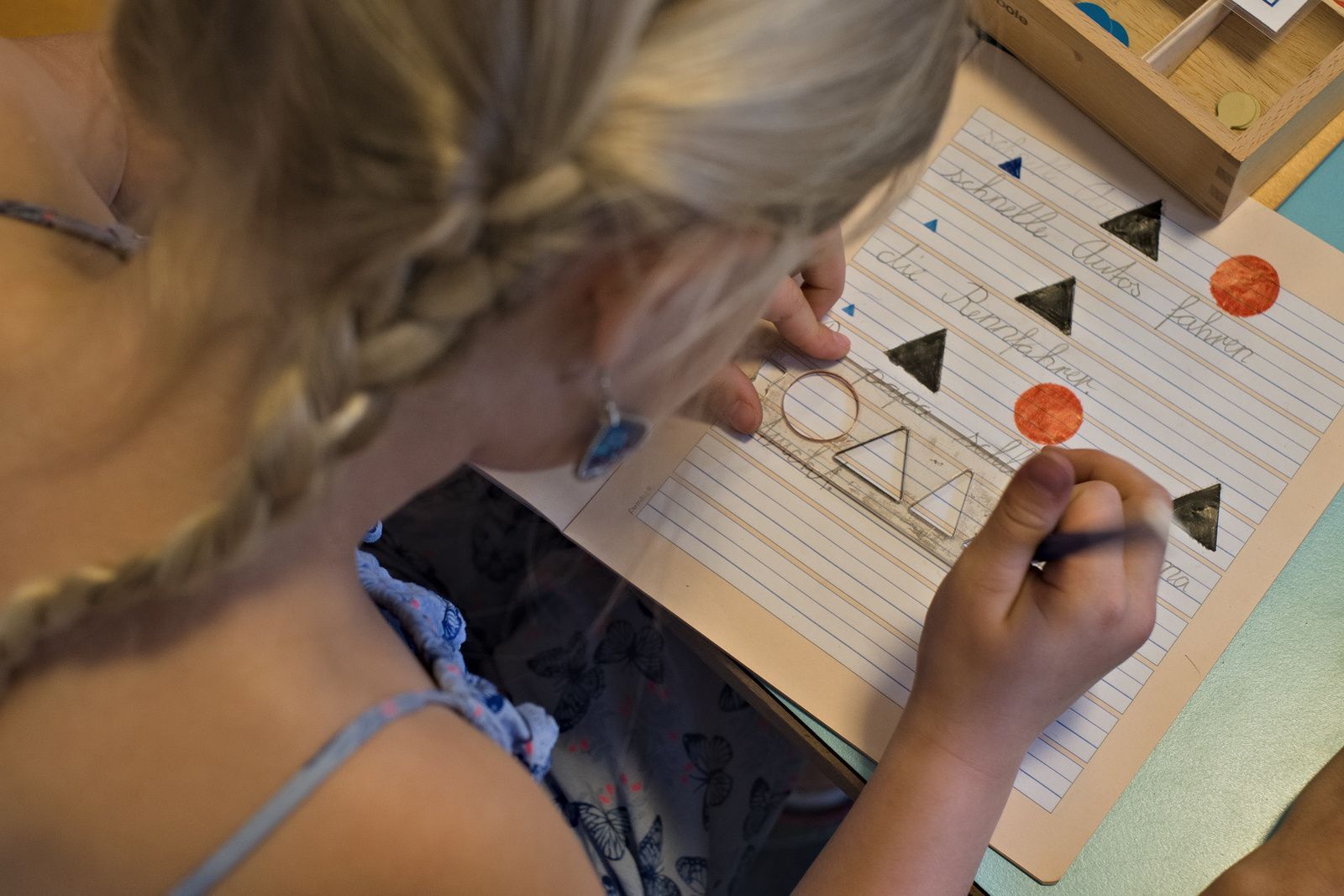 A little girl is writing on a piece of paper with a ruler