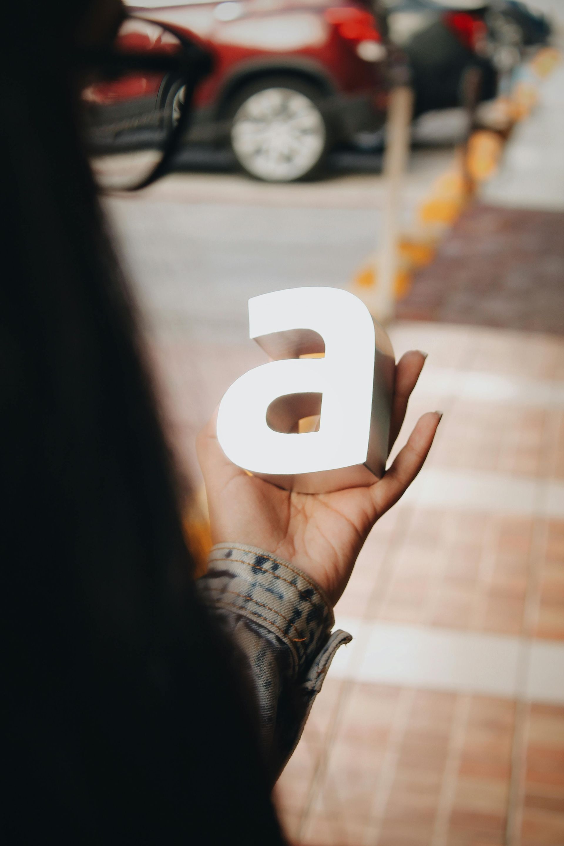 A person is holding a white letter a in their hand.