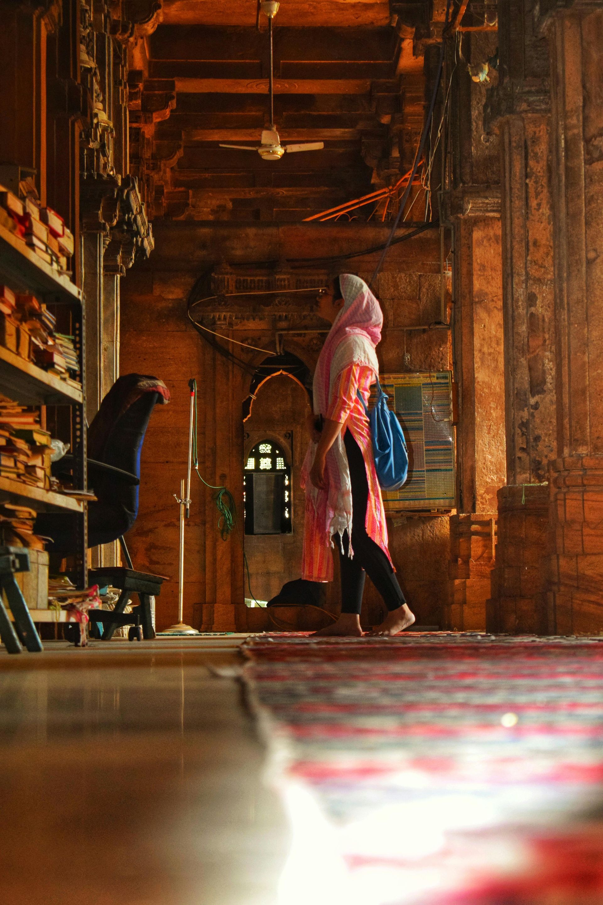 A woman in a hijab is walking through a very old building.