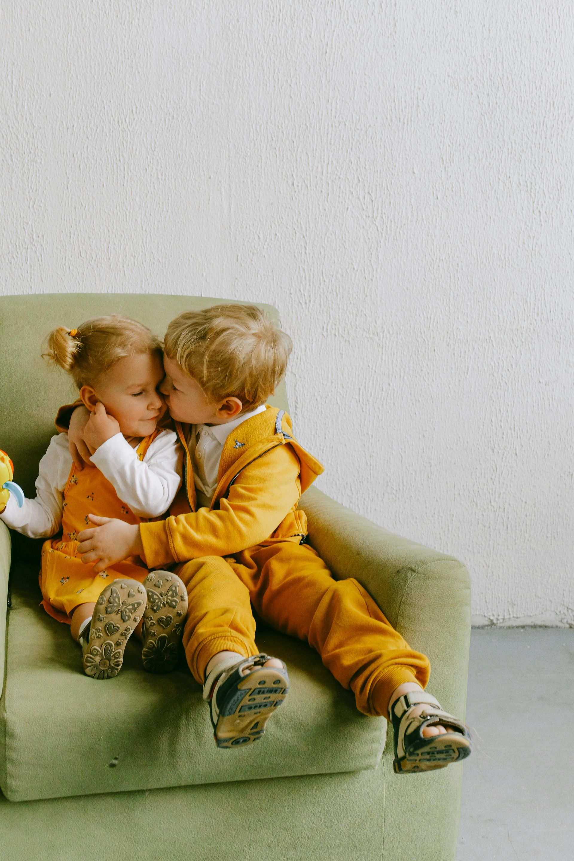 A boy and a girl are sitting in a chair hugging each other.