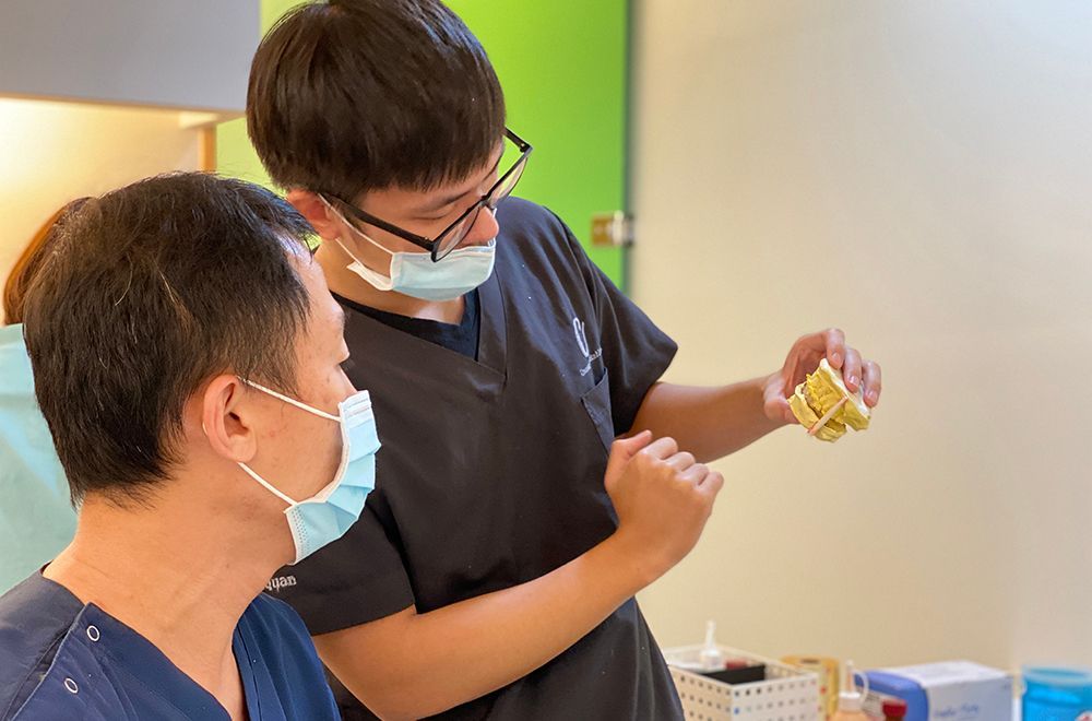 A dentist is talking to a patient in a dental office while wearing a mask.