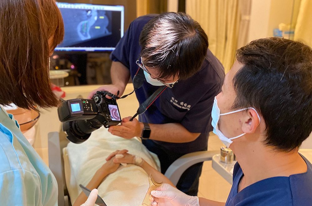 A dentist is taking a picture of a patient with a camera.