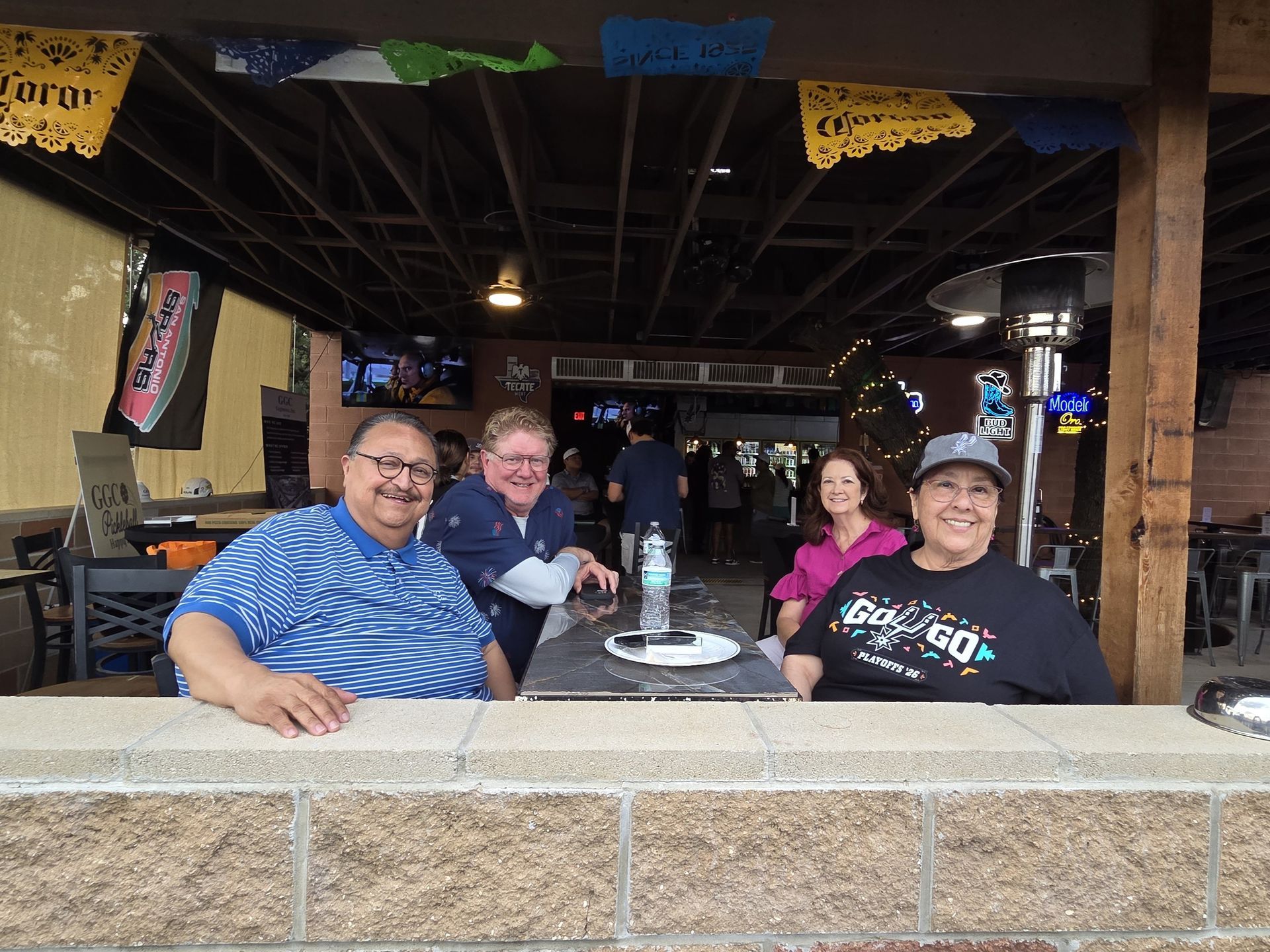 Four GGC team members smiling at a table in a rustic outdoor patio venue for a GGC Engineers, Inc. team building event.