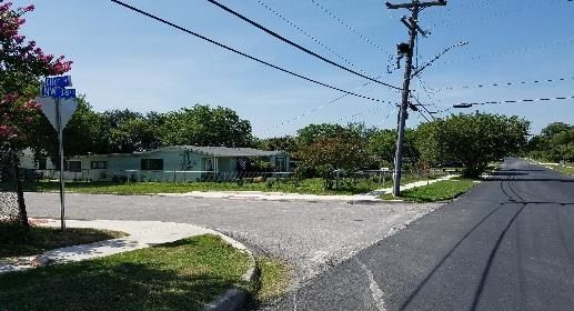 A suburban street with power lines and a small house under clear skies.