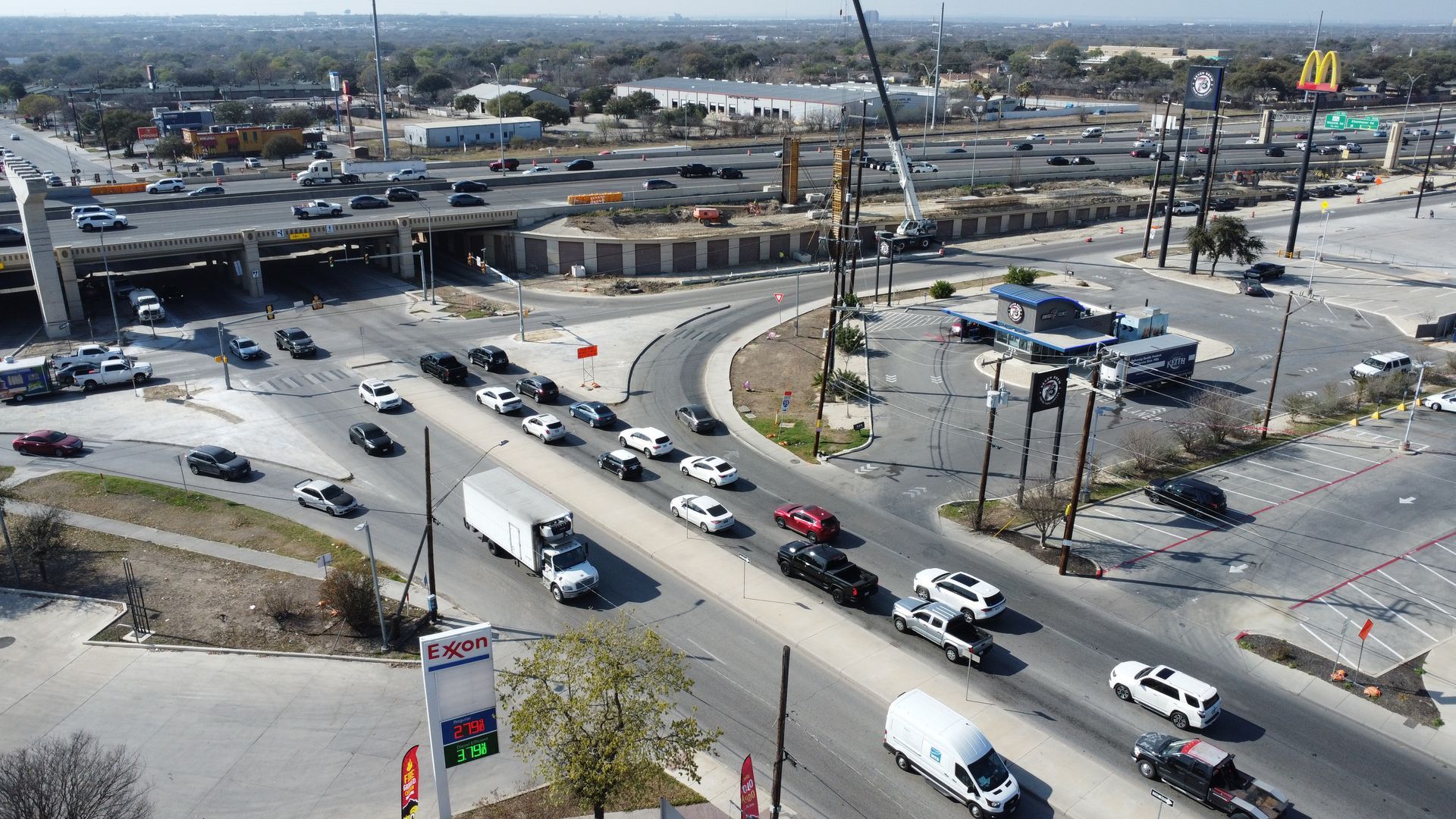 Aerial view of a busy highway interchange with cars, overpass, and surrounding urban roads.