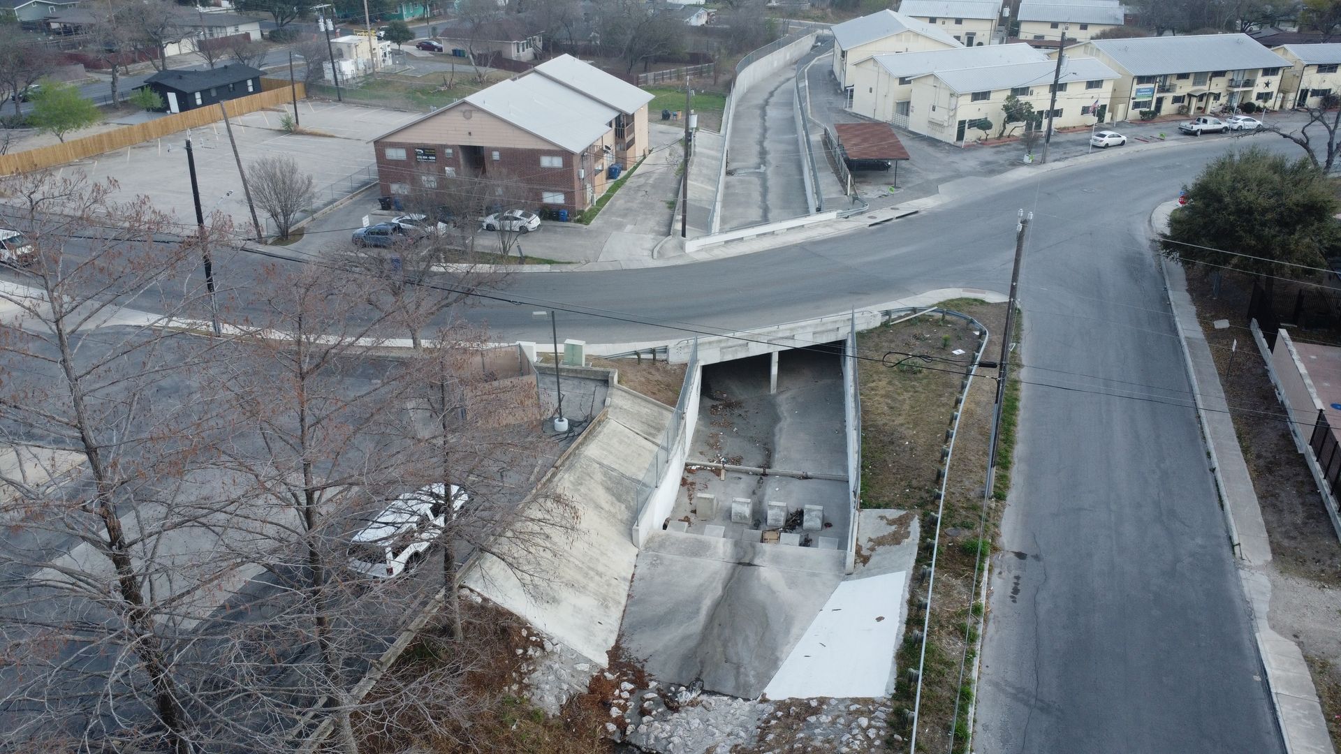 Concrete drainage channel under road bridge with concrete retaining walls.