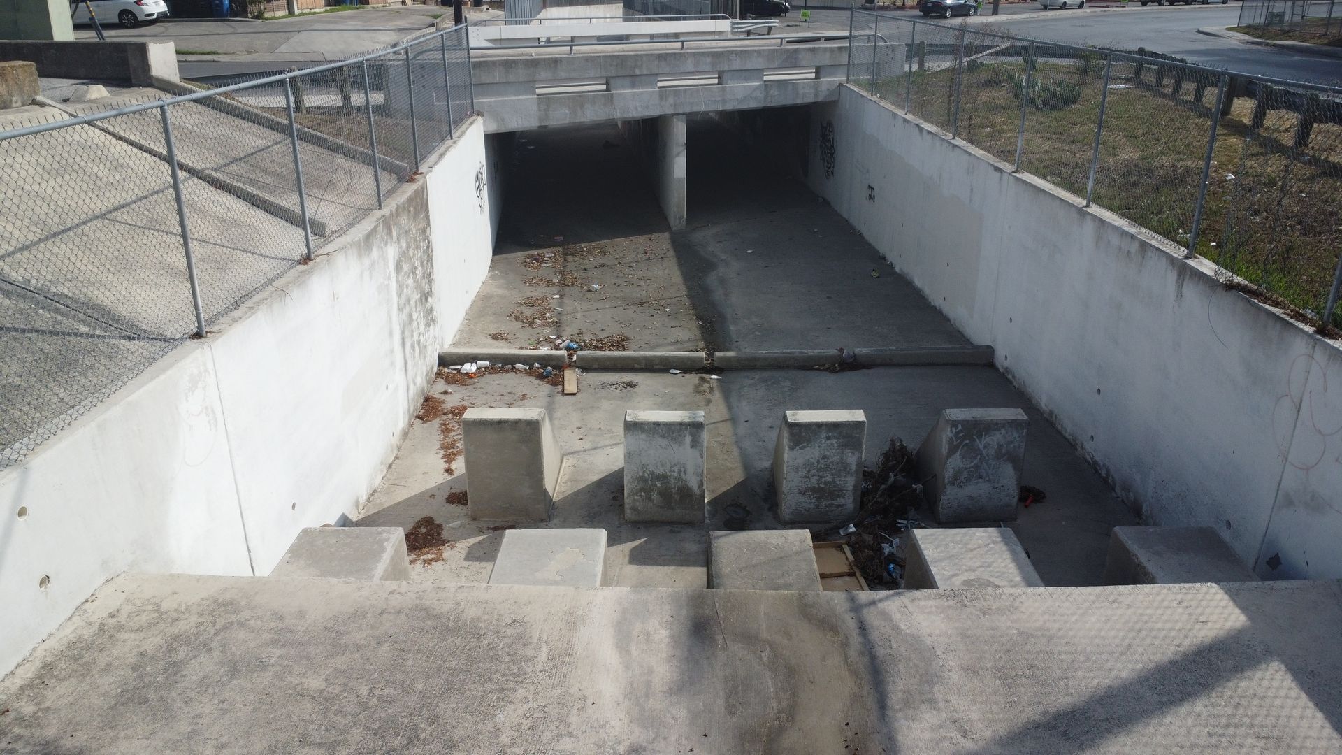 Empty concrete drainage channel running between retaining walls .