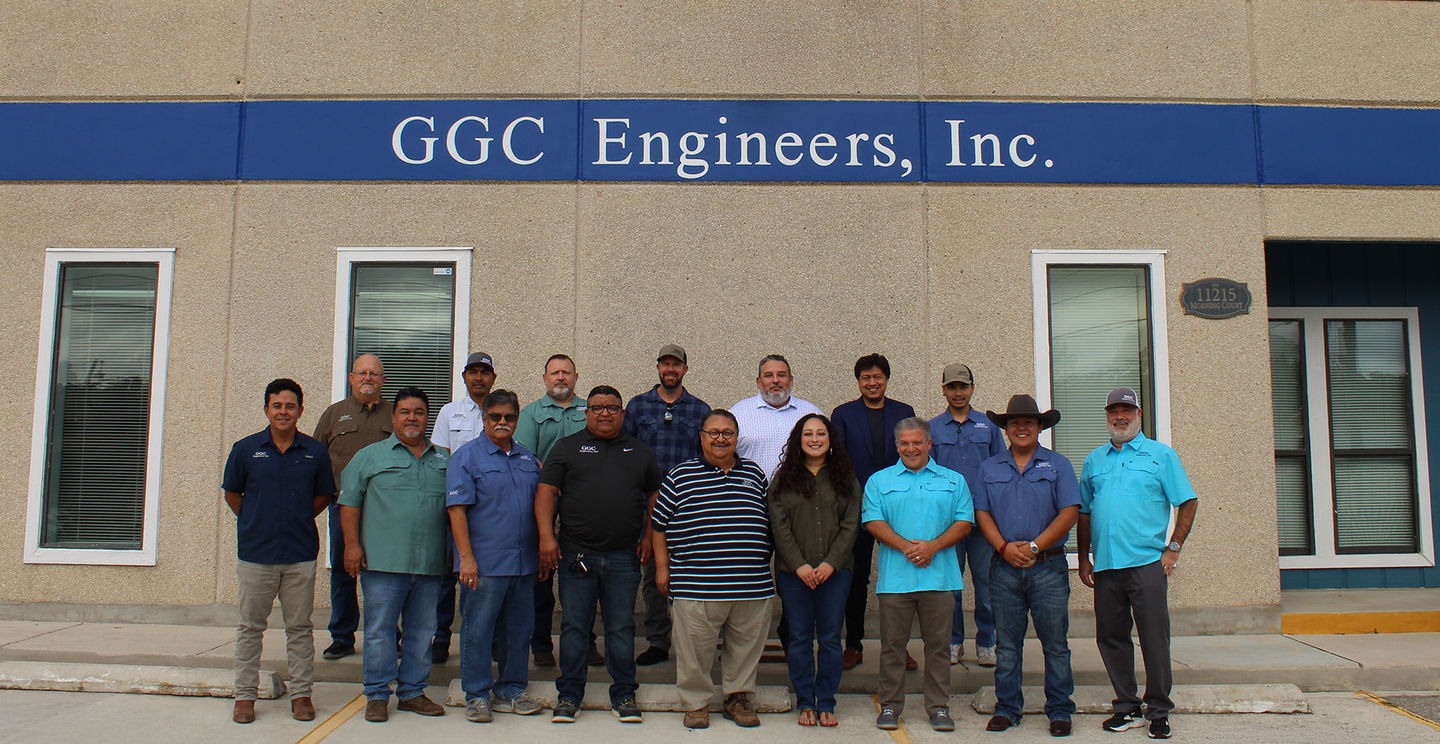 Group of staff posing in front of GGC Engineers, Inc. building with blue signage.