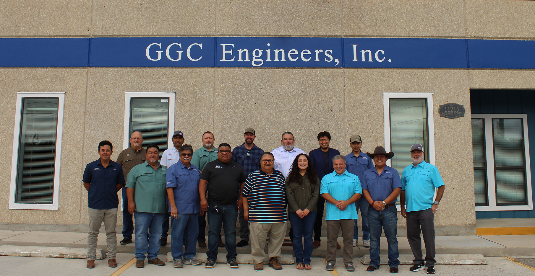 Group of staff posing in front of GGC Engineers, Inc. building with blue signage.