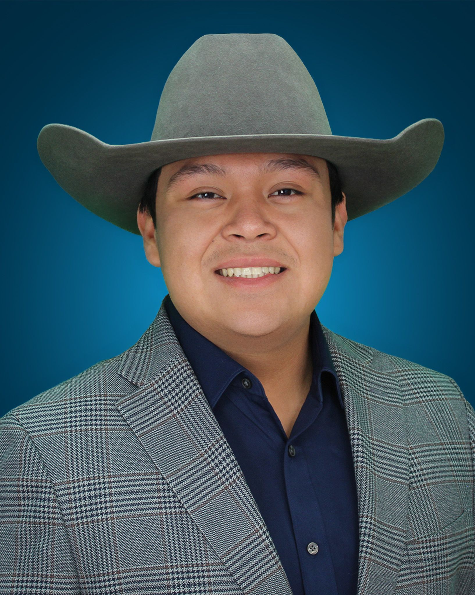 Man wearing a cowboy hat, blazer, and dark blue shirt smiling in front of a blue gradient backdrop.