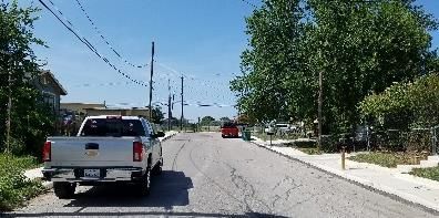 A silver pickup truck parked on a street with power lines. Trees and a blue sky are in view.